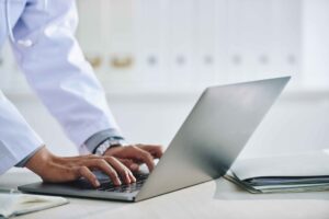 hands-unrecognizable-female-doctor-using-laptop-office-scaled-1